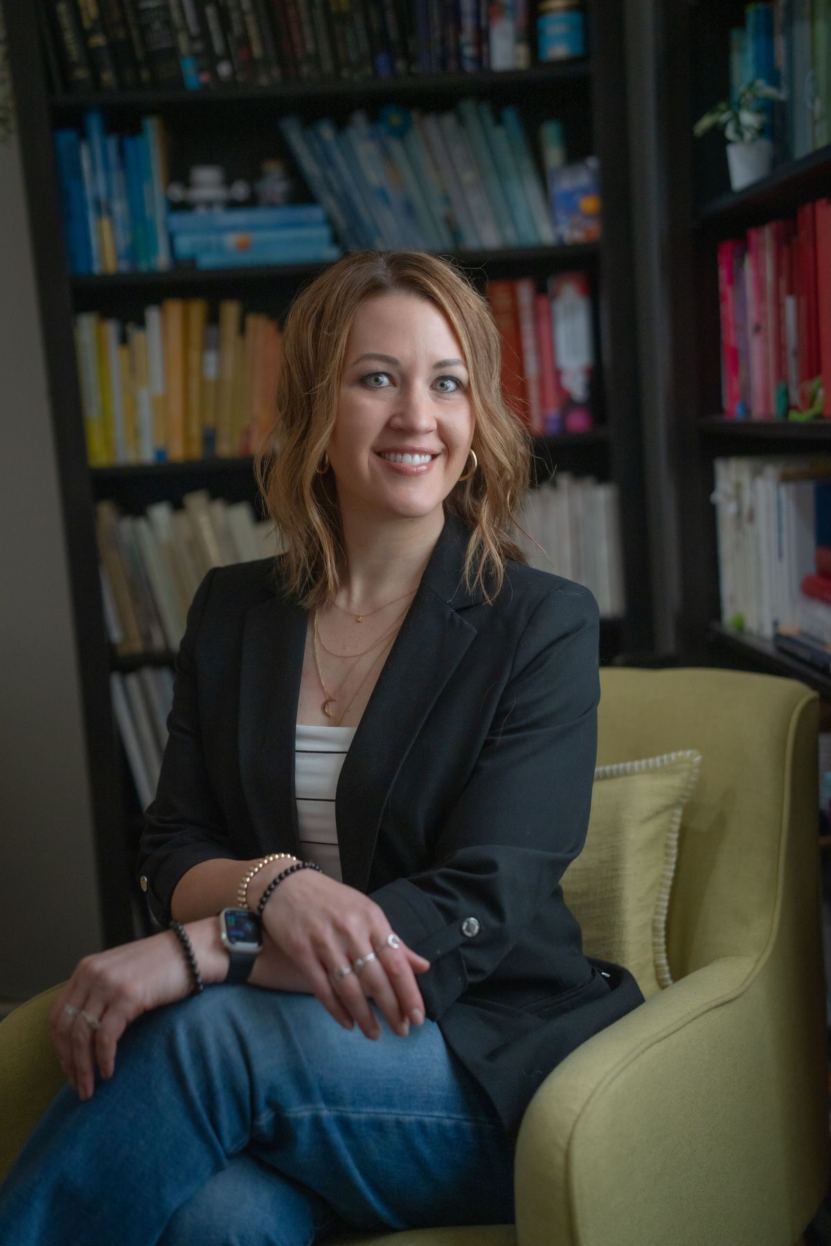 Aly Webster seated in a yellow armchair in her office