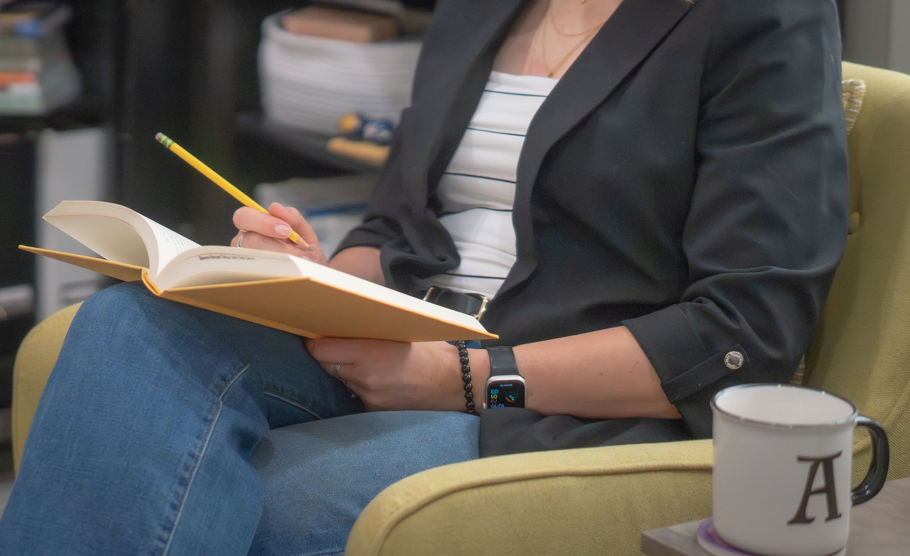 Aly writing in a journal in her office armchair