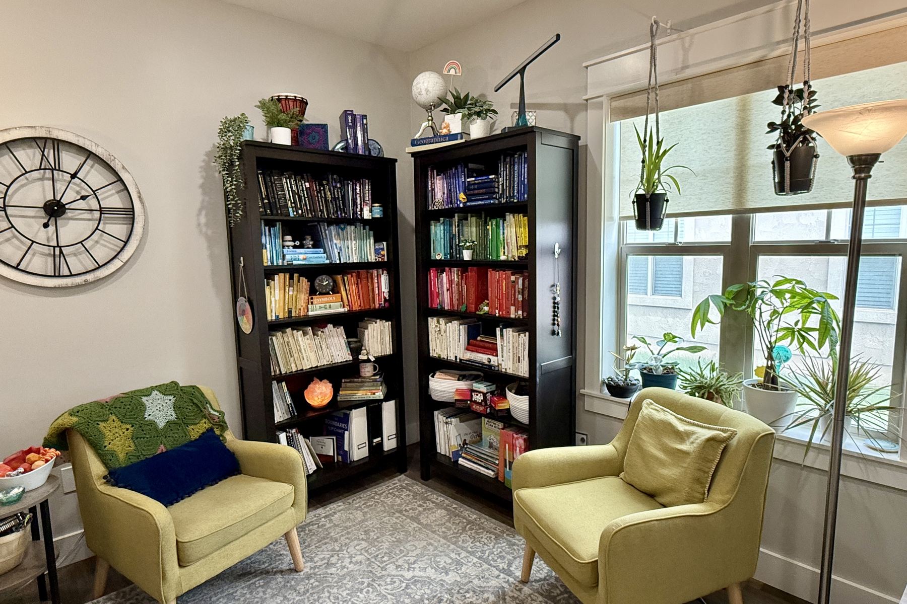 Two armchairs and color-sorted bookshelves in Aly's office in Ammon, Idaho