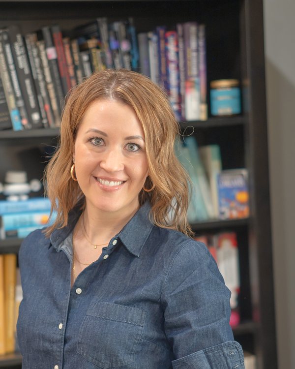 Aly standing in front of her bookshelves